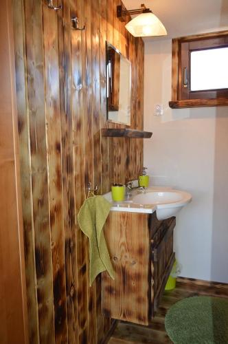 a bathroom with a sink and a wooden wall at Drevený Raj Apartmán in Hrabušice
