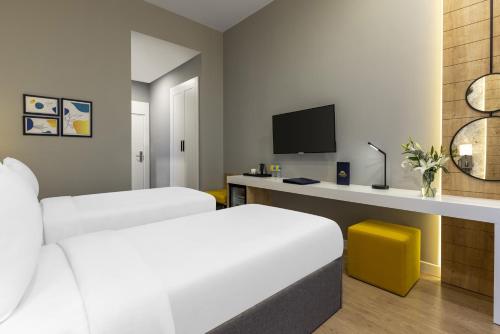 a hotel room with two beds and a desk with a tv at Days Inn & Suites by Wyndham Esenyurt in Istanbul