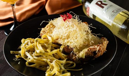 a black plate with pasta and a bottle of wine at Hotel San Juan Internacional in Bucaramanga