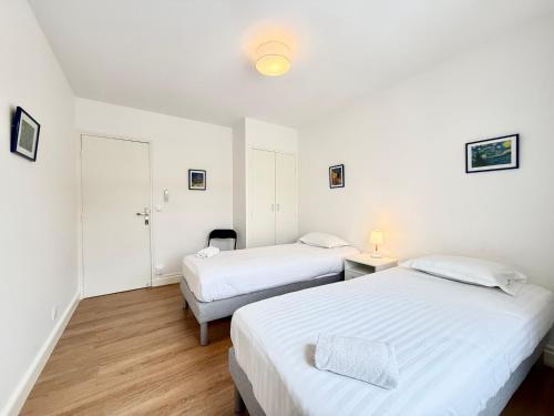 deux lits dans une chambre aux murs blancs et au parquet dans l'établissement Moderne - Terrasse - Proche plages, à Carqueiranne
