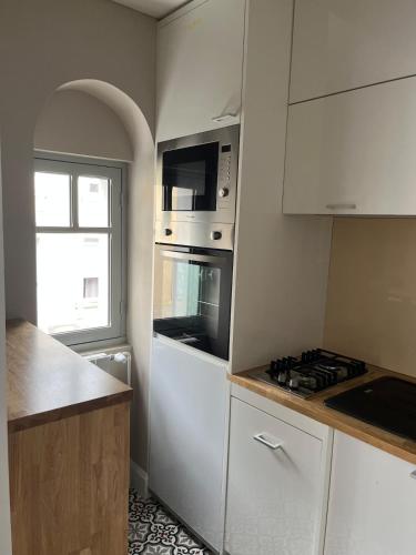 une cuisine avec des armoires blanches et un four à plaques de cuisson dans l'établissement Appartement Quartier Jardin Public, à Parthenay
