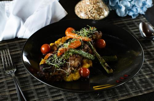 a black plate of food with vegetables on a table at Hotel San Juan Internacional in Bucaramanga