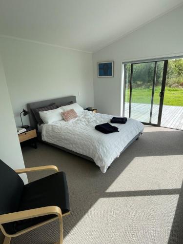 a bedroom with a bed and a chair in it at Clifton Bay Cottage in Te Awanga