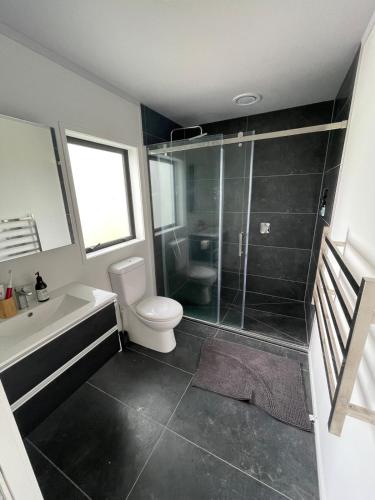 a bathroom with a shower and a toilet and a sink at Clifton Bay Cottage in Te Awanga