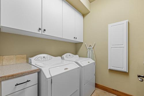 a laundry room with two washes and white cabinets at Lady Luck by the Beach - Downtown Greystone unit with air conditioning in McCall