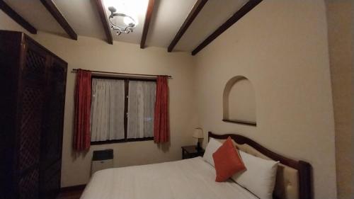 a bedroom with a bed and a window with red curtains at Mansión de la Bolivia in La Paz