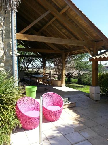 a patio with two pink chairs under a pavilion at Le Clos d'Any in Fontet