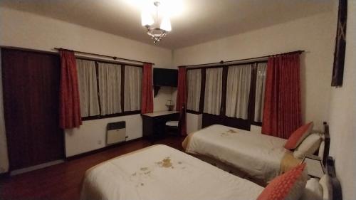 a hotel room with two beds and red curtains at Mansión de la Bolivia in La Paz