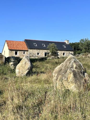 a house in a field with rocks in front of it at Menhirs et Moutons Ouessant in Plouëc-du-Trieux