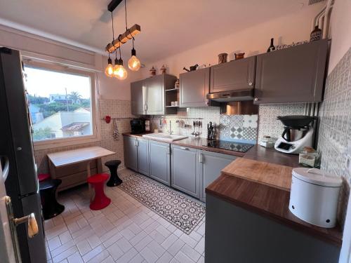 une cuisine avec des placards gris, une table et une fenêtre dans l'établissement Lna, à La Celle-sous-Gouzon