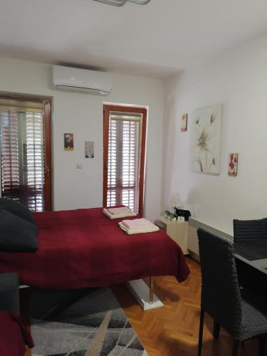 - une chambre avec un lit rouge et deux fenêtres dans l'établissement Apartman Lala, à Vrnjačka Banja