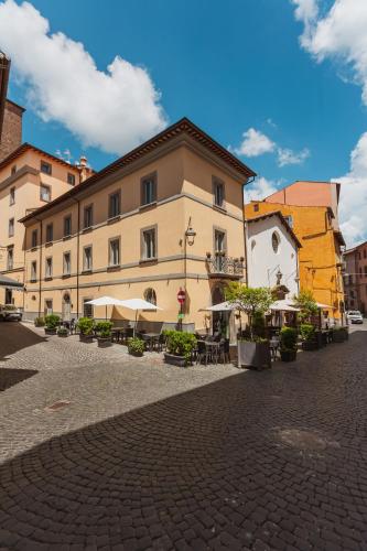 a building with tables and umbrellas on a street at Palazzo San Biagio in Viterbo