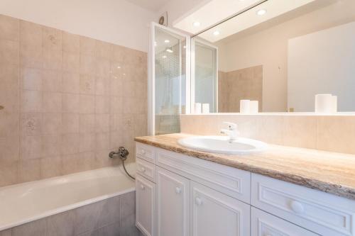 a bathroom with a sink and a tub and a mirror at Appartement cocooning in Fréjus