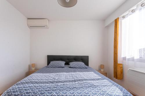 a bedroom with a bed with a blue comforter and a window at Appartement cocooning in Fréjus