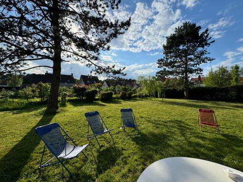 trois chaises assises dans l'herbe à côté d'une table dans l'établissement Maison avec Jardin Spacieux proche Touquet, à Cucq