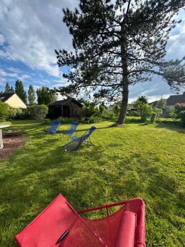 un groupe de chaises bleues dans une cour avec un arbre dans l'établissement Maison avec Jardin Spacieux proche Touquet, à Cucq