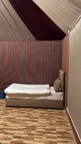 a bed in a room with a red wall at Ata wadi rum in Disah