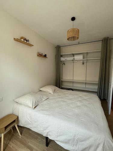 une chambre avec un grand lit blanc et une chaise dans l'établissement T2 lumineux et tout équipé centre Annonay, à Annonay