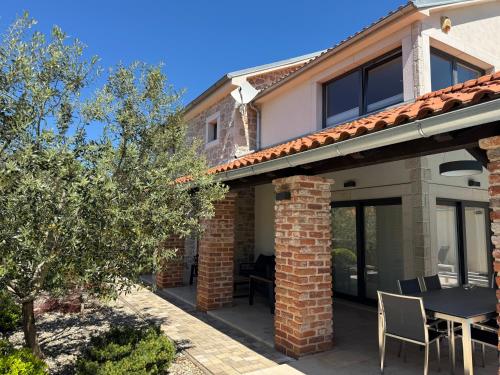 a house with a patio with a table and chairs at Villa Kvarner in Krk