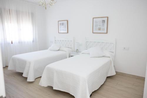 - 2 lits dans une chambre blanche aux murs blancs dans l'établissement Apartamentos Lua, à O Grove