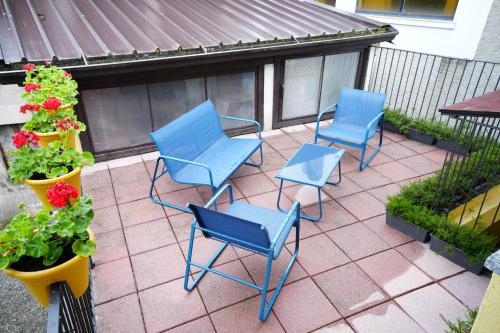 three blue chairs and flowers on a patio at The One Malpensa Rooms in Vizzola Ticino