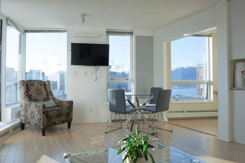 Una sala de estar con mesa y sillas y ventanas. en Gorgeous Water View Unit in Downtown Vancouver, en Vancouver