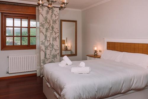 una camera da letto con un grande letto bianco con asciugamani sopra di Entorno rural con piscina by CABANA Rentals a Budiño