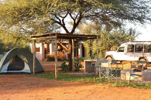 a tent and a table in a yard with a tree at Orpheus Inn Camping in Kaneb Pos