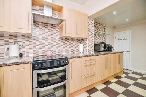 a kitchen with wooden cabinets and a checkered floor at Modern 3 bedroom 2 bathroom Free Wifi Central Location in Middlesbrough