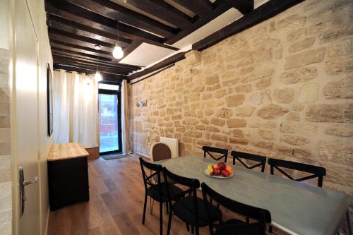 ein Esszimmer mit einem Tisch, Stühlen und einer Steinmauer in der Unterkunft Apart of Paris - Souplex Loft Apartment - Le Marais in Paris