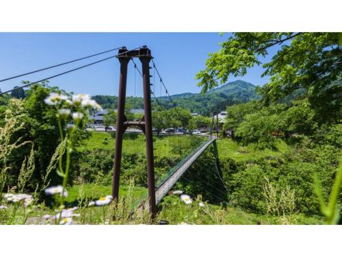 a suspension bridge over a field with mountains in the background at TAKAYANAGI JONNOBI VILLAGE - Vacation STAY 90875v in Kashiwazaki