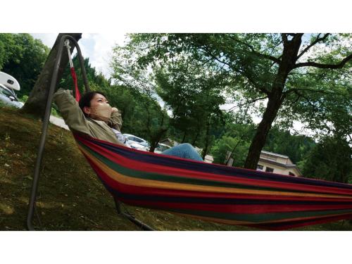 a man sitting in a hammock in a park at TAKAYANAGI JONNOBI VILLAGE - Vacation STAY 90875v in Kashiwazaki