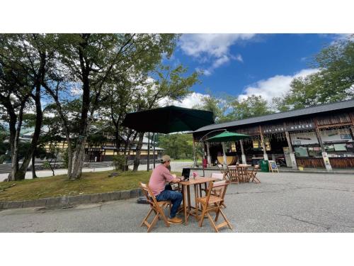 a man sitting at a table in front of a building at TAKAYANAGI JONNOBI VILLAGE - Vacation STAY 90863v in Kashiwazaki