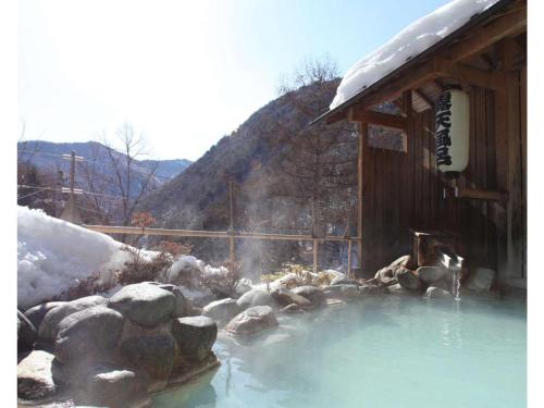 a hot tub with snow on it next to a cabin at Shirafune Grand Hotel - Vacation STAY 85694v in Matsumoto