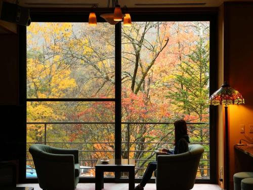 a woman sitting in a chair in front of a large window at Shirafune Grand Hotel - Vacation STAY 85694v in Matsumoto