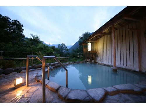 a large swimming pool with a building and a house at Shirafune Grand Hotel - Vacation STAY 85694v in Matsumoto