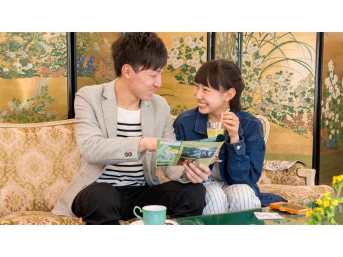 a man and a woman sitting on a couch reading a book at Kinugawa Park Hotels - Vacation STAY 96213v in Nikko