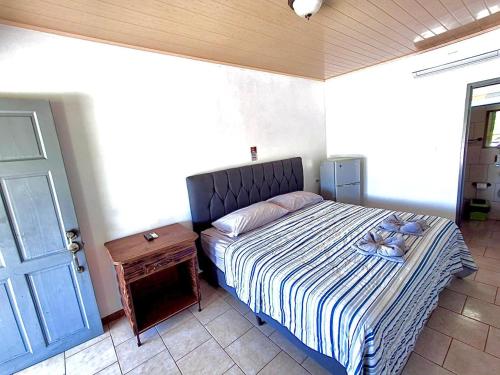 a bedroom with a bed with a blue door and a table at Hotel Cabinas el Tecal in Uvita