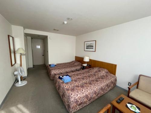 une chambre d'hôtel avec deux lits et une chaise dans l'établissement Kitaguni Grand Hotel - Vacation STAY 97231v, à Oshidomari