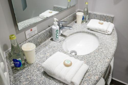 a bathroom counter with a sink with towels and a mirror at ibis Quito in Quito