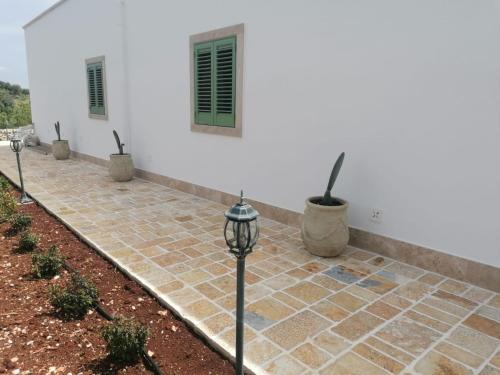 a white building with a courtyard with potted plants at Antichi Saperi - Villa con piscina Cisternino in Cisternino