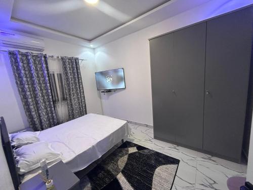 a small bedroom with a bed and a tv at SKA Zac Mbao in Rufisque
