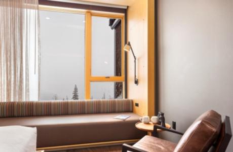 a bedroom with a window and a couch and a chair at Humbird Hotel in Sandpoint