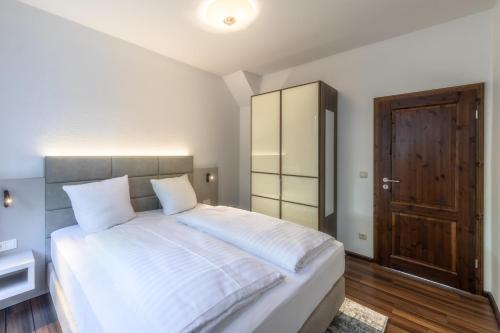 a bedroom with a large white bed and a wooden door at Ferienwohnung "Kleines Meer" in Waren