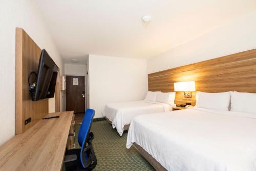 a hotel room with two beds and a desk and a tv at Holiday Inn Express San Jose Costa Rica Airport by IHG in Alajuela City