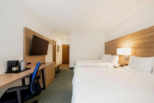 a hotel room with two beds and a desk and a tv at Holiday Inn Express San Jose Costa Rica Airport by IHG in Alajuela City