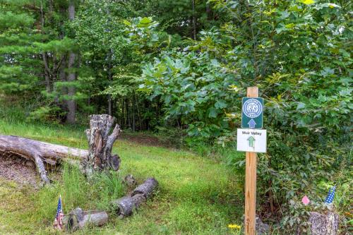 a sign in the grass next to a tree at Hemlocks Over Muir in Rogers