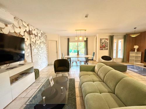 - un salon avec un canapé vert et une télévision dans l'établissement Caporizon - Villa Puy d'Aiguillon- Piscine - 6 personnes, à Les Pies