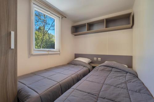 deux lits dans une petite pièce avec une fenêtre dans l'établissement Camping les mizottes, à Saint-Michel-en-lʼHerm