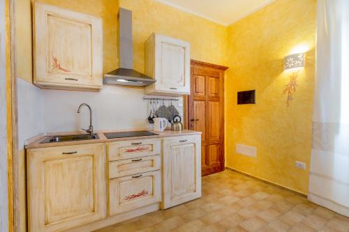a kitchen with wooden cabinets and a sink at Palazzo Beddoro in San Pantaleo